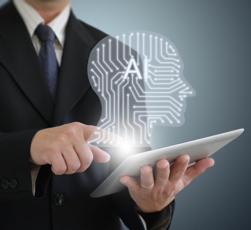 Zakelijke man in pak bedient een tablet waarop een digitaal AI-hoofd met circuitpatroon verschijnt.