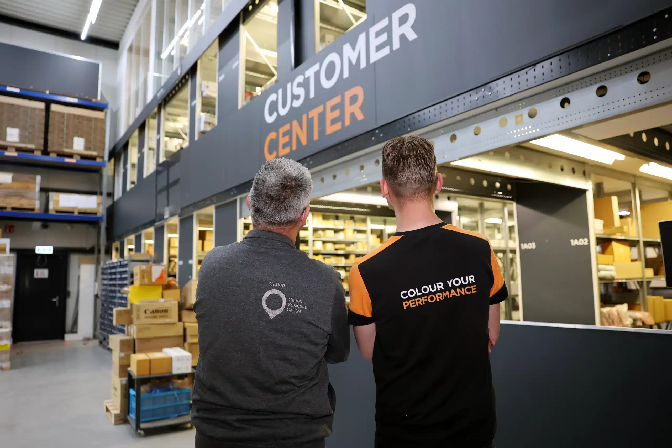 Collega's van Marloes Brouwers in gesprek met een collega bij het Customer Center in een magazijnomgeving