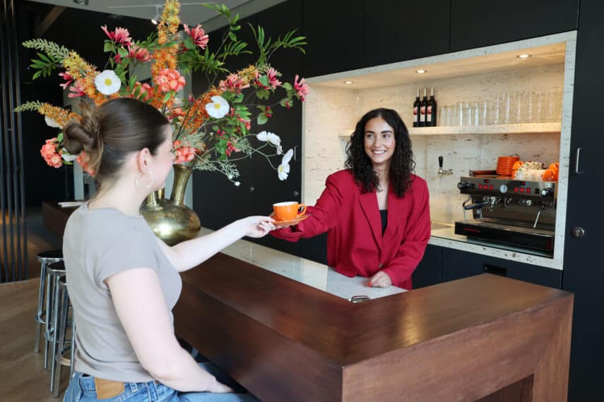 Collega Isa geeft aan onze collega Manon een koffie