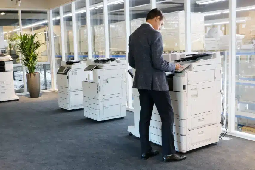 Productoverzicht van Canon imageRUNNER printers in een moderne kantooromgeving, met een medewerker die een apparaat bedient.