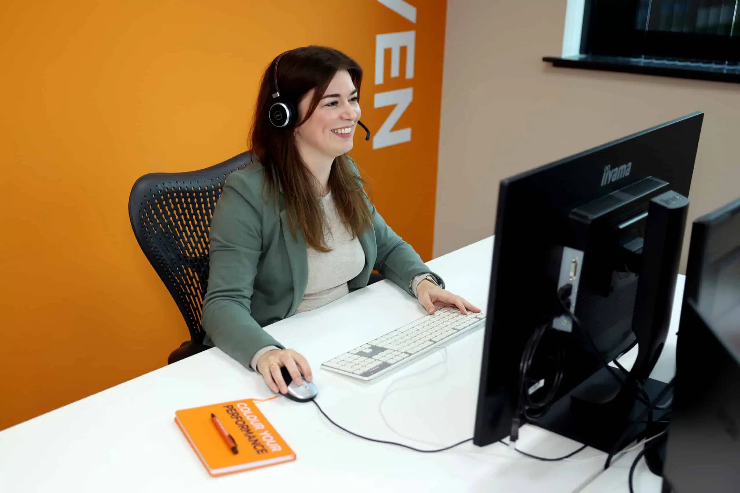 Medewerker met headset aan het werk in een moderne kantooromgeving – relevant voor kopieermachine leasen.