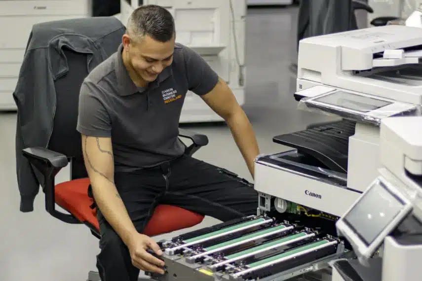 Engineer voert printeronderhoud uit aan een Canon multifunctionele printer in een professionele werkomgeving.