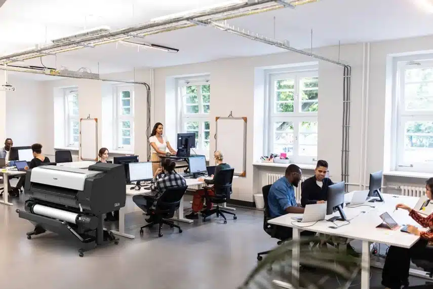 Moderne kantoorruimte met meerdere werkplekken en een grote professionele printer, ideaal als beste kantoorprinter voor bedrijven met hoge printvolumes.