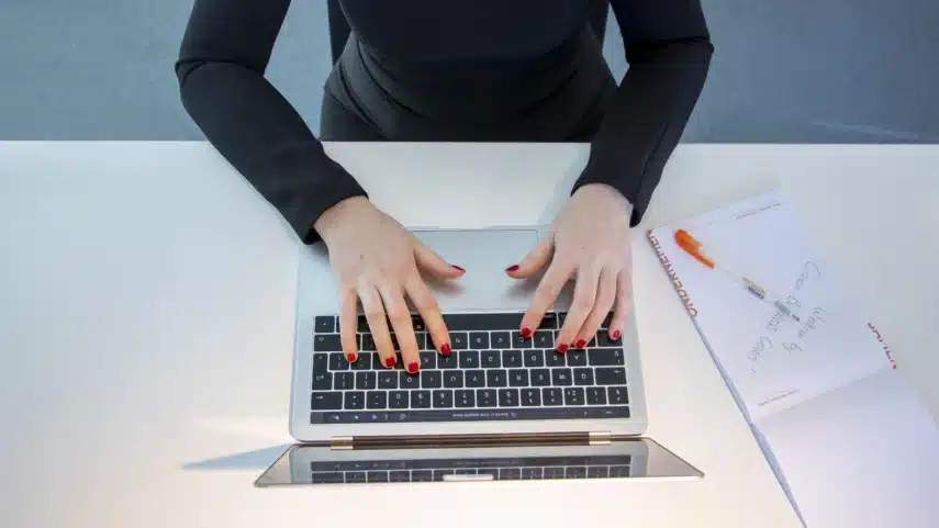 Canon printer helpdesk – medewerker werkt op laptop met notitieblok op bureau.