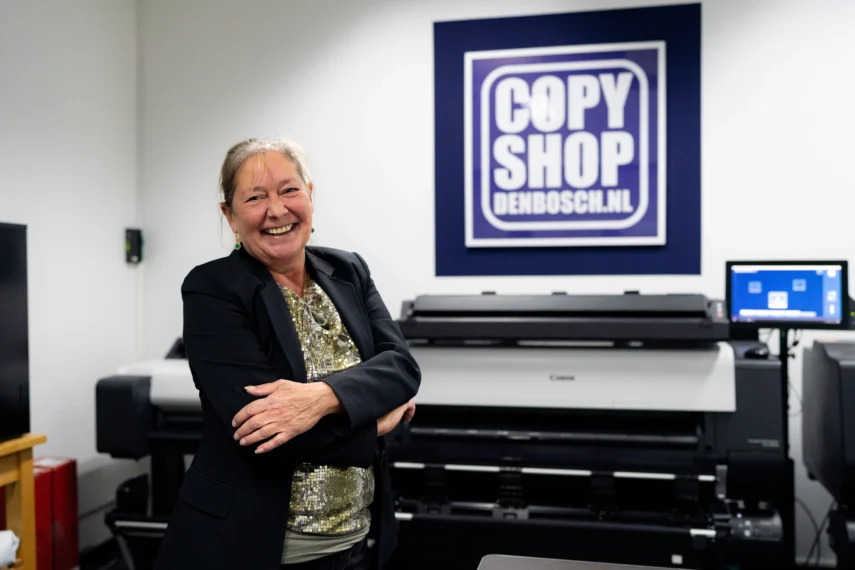 Canon grootformaat printer bij Copyshopdenbosch met bedrijfslogo op de achtergrond.