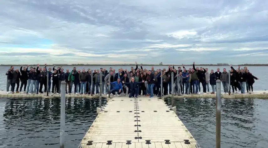 Ontdek onze cultuur tijdens de Mega Medewerkers Getaway met een grote groep collega’s op een steiger aan het water.
