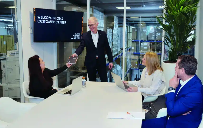 Overlegtafel met meerdere medewerkers in een kantooromgeving die zakelijke printoplossingen bespreken voor een kantoor met 10 medewerkers.