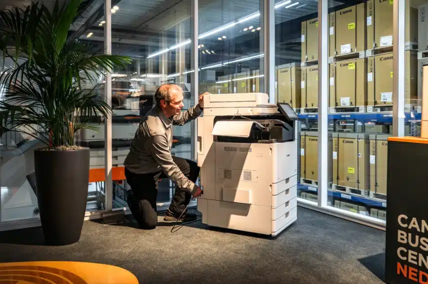 Technisch specialist installeert een multifunctionele printer voor bedrijven als onderdeel van professionele printerservice en support.