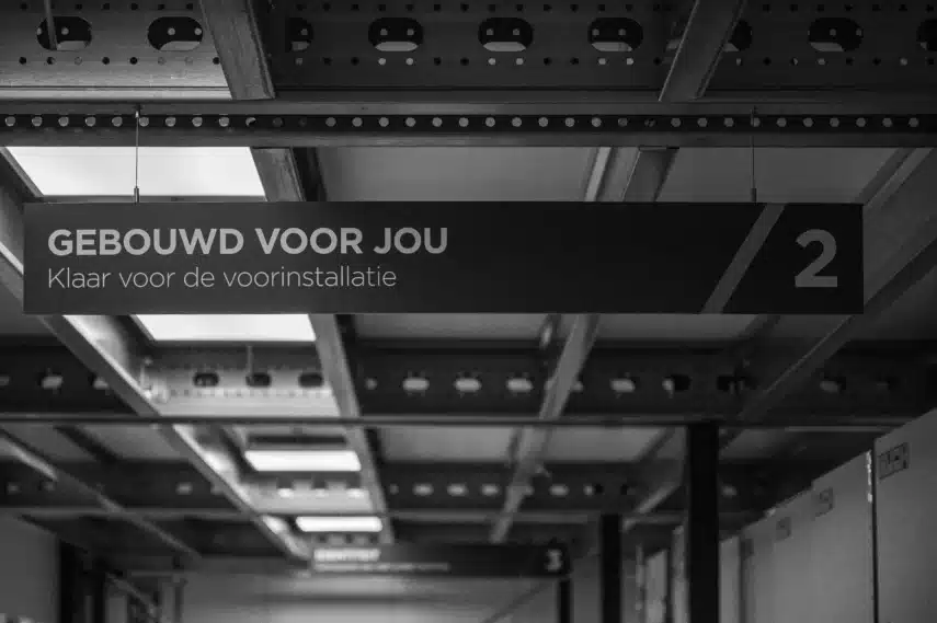 Bord met de tekst 'Gebouwd voor jou' boven een installatiezone waar multifunctionele printers worden voorbereid voor gebruik.